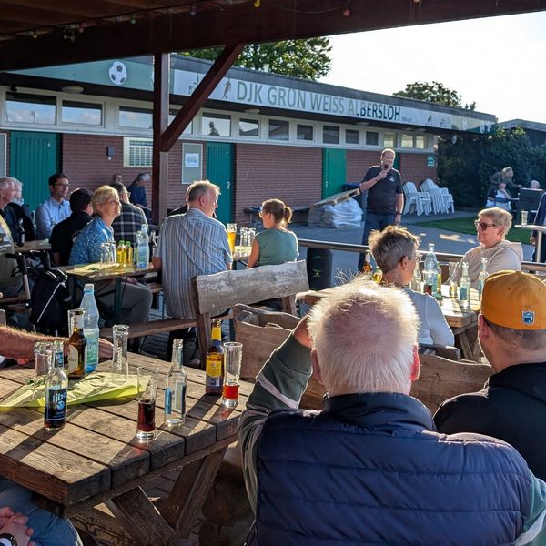 Gruppe von Menschen auf Terrasse hört 2 Rednern zu